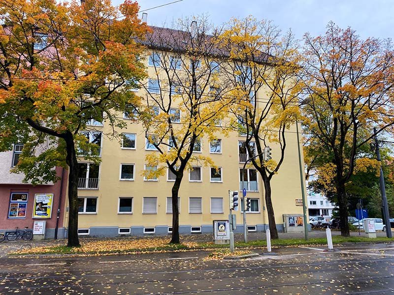 Mehrfamilienhaus mit Straße und Bäumen