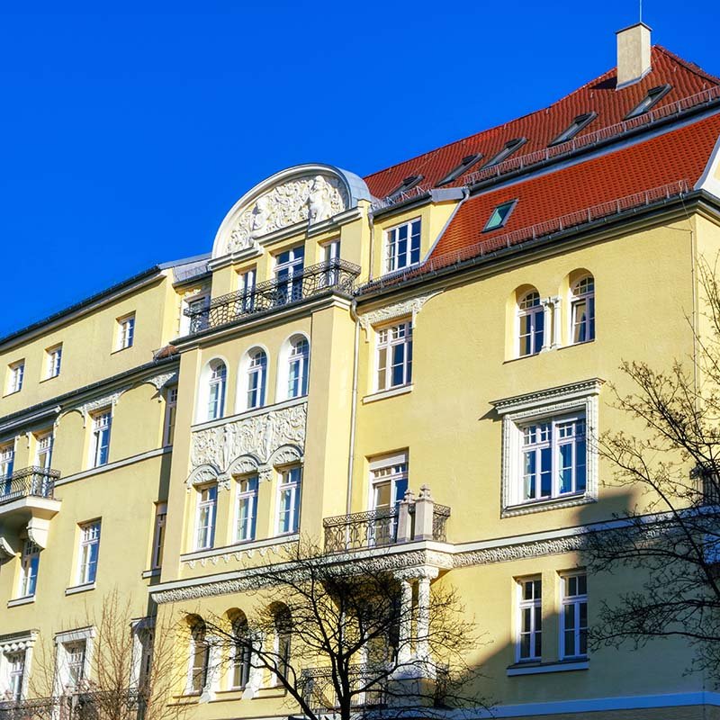 Klassizistisches Mehrfamilienhaus mit vier Stockwerken und rotem Ziegeldach in München